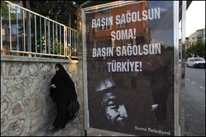 A woman walks past a bus stop with a poster offering condolences in Turkish to Soma and Turkey, in Soma, western Turkey, where the mine accident occurred.