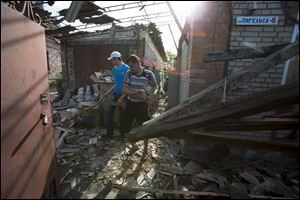 Relatives of Yekaterina Len, 61, try to clean debris in her destroyed house following a shelling in Slovyansk, eastern Ukraine, today. Slovyansk has been the major fighting ground between pro-Russian insurgents and Ukrainian government troops in eastern Ukraine. 