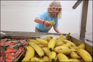 Laura Martin, 10, selects a banana during lunch at  Reynolds Elementary in South Toledo. Each lunch includes two fruits, one protein, one vegetable, and milk.  The school adopted the healthier menu in the past year.