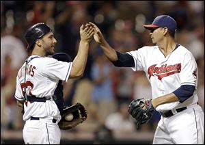 Cleveland Indians catcher George Kottaras, left, congratulates relief pitcher Carlos Carrasco after struck out Los Angeles Angels' Josh Hamilton for the final out.