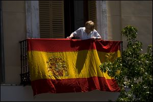 A woman hangs a Spanish flag on her balcony in front of the Royal Palace in Madrid, Spain, today, a day before 46-year-old Prince Felipe will be proclaimed king .