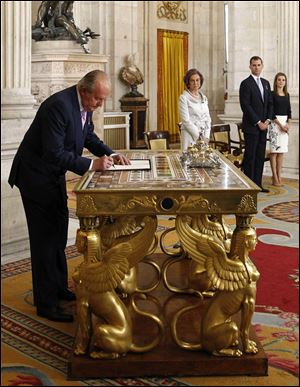 Spain’s King Juan Carlos, left, signs an abdication law in the presence of Queen Sofia, Spain's Crown Prince Felipe and Princess Letizia  during a ceremony at the Royal Palace Wednesday.  Juan Carlos formally ratified the law, signing a legislation setting out the legal framework for the handover so his 46-year-old son can be proclaimed King Felipe VI.