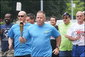 Toledo Deputy Chief George Kral, center, carries the torch as he leads officers and Special Olympians from the downtown Safety Building to Fifth Third Field. It’s part of a week-long run in which police pass off the ‘‍Flame of Hope’ torch from one jurisdiction to the next, ending in Columbus.