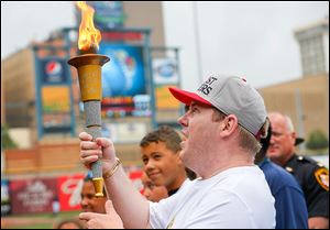 Steve Hanf of Toledo, with the Special Olympics, holds the torch aloft before the Mud Hens game at  Fifth Third Field. He carried the torch into the stadium.