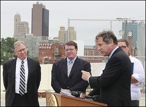 Lucas County Engineer Keith Earley, left, and TMACOG transporta-tion director Warren Henry listen as U.S. Sen. Sherrod Brown speaks in Toledo.