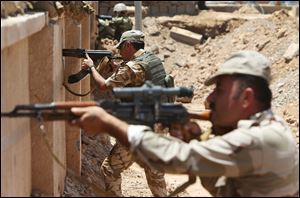 Kurdish peshmerga fighters take their positions behind a wall on the closest front line with militants from the al-Qaeda-inspired Islamic State in Iraq and the Levant in Tuz Khormato, Iraq.