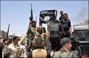  Iraqi security forces hold up a flag of the Islamic State in Iraq and the Levant they captured during an operation to regain control of Dallah Abbas north of Baqouba, the capital of Iraq's Diyala province, 35 miles (60 kilometers) northeast of Baghdad, Iraq.