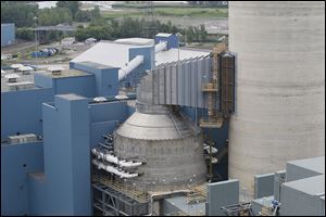 At right, the concrete building which connects to the stack houses the ‘‍scrubbers,’ which use limestone to clean the exhaust Combined with a catalytic reduction system the process also removes mercury from the plant's emissions. A byproduct of the process is gypsum, which is the main ingredient in sheetrock.