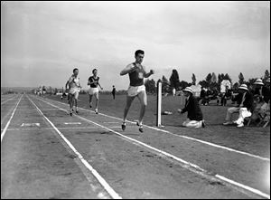 Louis Zamperini of he University of Southern California, breaks the tape and record with a time of 4:16.3 to win the mile run in the Pacific Coast Conference Track and Field meet the University of Washington Stadium in Seattle in May, 1939.