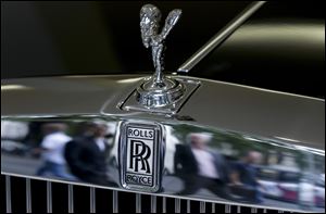 Pedestrians are reflected in the chrome work under The Spirit of Ecstasy on the front of a Rolls- Royce car, in a show room in London, Tuesday, July 8, 2014. Sales of luxury Rolls-Royce cars, which cost hundreds of thousands of dollars, have soared worldwide.  The Britain-based manufacturer said Tuesday that global sales in the first half of the year were up 33 percent compared with the same period in 2013. (AP Photo/Kirsty Wigglesworth)