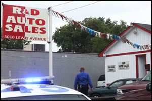 Law enforcement officials investigate the scene of a botched robbery and murder at R&D Auto Sales Tuesday, July 8, 2014, in North Toledo.