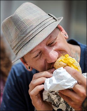 Chris Zielinski of Toledo eats kielbasa on Saturday during the Lagrange Street Polish Festival.