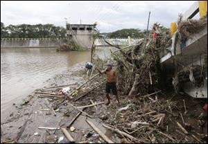 A resident salvages items from the debris at a collapsed bridge today at Batangas city, 62 miles south of Manila, Philippines. 