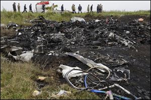 Rescue workers walk at the site of a crashed Malaysia Airlines passenger plane near the village of Hrabove, Ukraine, eastern Ukraine Friday, July 18, 2014.