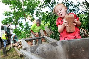 Susan White, center, and Elizabeth Curtis, 5, right, both from the neighborhood, collect bricks to use for landscaping and keepsakes as a demolition crew works at the site of what was once Sylvan Pool.