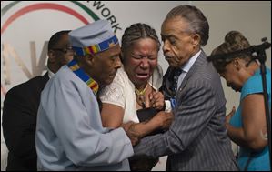 Esaw Garner, wife of Eric Garner, breaks down in the arms of Rev. Herbert Daughtry, center, and Rev. Al Sharpton, right, during a rally Saturday for Eric Garner at the National Action Network headquarters.