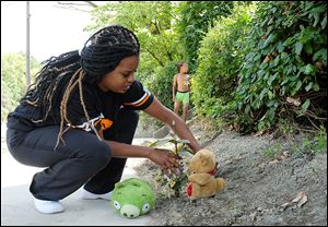 Jacqueline Bush puts flowers and stuffed animals on Colling-wood Boulevard where Tyler McIntoush, 16, was killed. Ms. Bush was the youth’s neighbor.