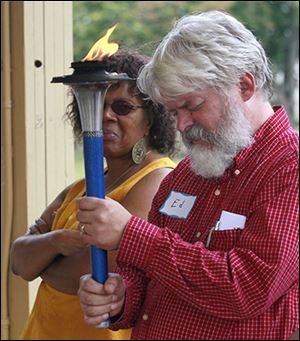 Ed Heilman, pastor of Park Church United Church of Christ, prays as he holds the peace torch.