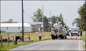 Authorities stand near debris left from an overnight plane crash near the intersection of Hancock County Roads 18 and 216.