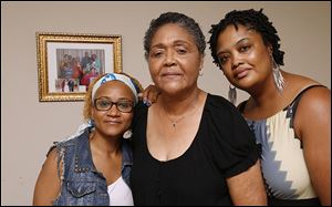 Jenny Brisbane, center, mourns the death of husband Dr. Samuel Brisbane with daughters Marie Brisbane, left, and Baendu Brisbane-Williams in Maumee.