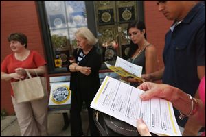 Members of the inaugural tour of Toledo Flavors Food Tours take a look at their itinerary outside Tony Packo's, their first food stop, near downtown Toledo. 