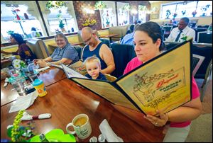 April Chappell, right, and her son, Ross Chappell, 2, scan the menu at the Original Pancake House on Monday. The restaurant was closed both Saturday and Sunday in response to the area’s water emergency.