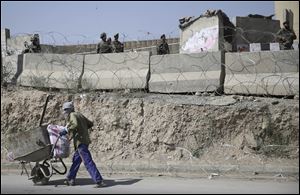 An Afghan laborer walks past a gate of Camp Qargh today in Afghanistan where a man dressed in an Afghan army uniform opened fire today on foreign troops.