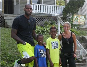 TV's Rehab Addict host Nicole Curtis, right, poses with LeBron James and his sons, LeBron, Jr., and Bryce at a rehab site on Monday in Akron.