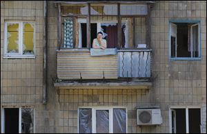 A local woman stands on her damaged balcony after morning shelling Saturday in Donetsk, eastern Ukraine. Several shells fell this morning in a northern Donetsk neighborhood, near the airport. No human casualties were registered.