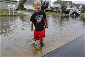 Ethan Rader, 5, of Perrysburg, fills his boots with water from heavy rains in the Brookhaven subdivision in Perrysburg.