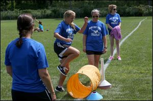 Belynda Crandall, left, watches her daughter Maddy Crandall, 14, center left, leap over an obstacle as other mothers, Lynn Arvay, center, and Ann Nolan, right, help lead exercises.