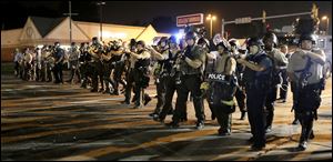 Police advance to clear people from the streets of Ferguson, Mo. Monday.