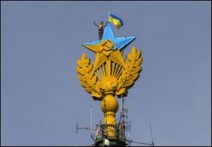 A worker takes a selfie before removing a yellow and blue Ukrainian flag attached by protesters atop Stalin-era skyscraper  in Moscow, Russia, today.