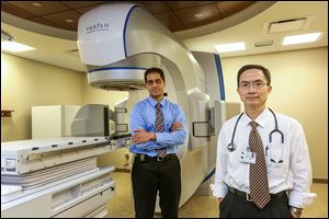 Dr. Krishna Reddy, assistant professor of radiology oncology, left, and Dr. Changhu Chen, professor and chairman of radiation oncology at the University of Toledo Medical College, stand by the stereotactic radiosurgery machine.