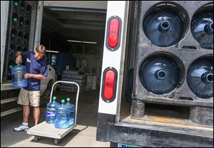 Scott Ormsby, president of the Collingwood Water Co., pulls water jugs off a company truck for a customer. 