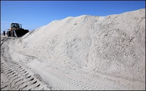 City crews use bulldozers to build up a sand berm in preparation for a storm surge in Long Beach, Calif.