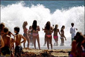 Beachgoers watch large waves crash on the shore at Seal Beach, Calif.