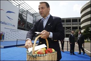 Polish Foreign Minister Radoslaw Tomasz Sikorski arrives at the meeting holding a basket of apples to protest against Russia's ban on food imports.