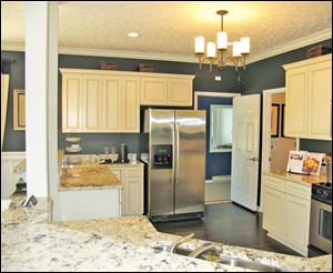 The kitchen’s antiqued white cabinets and dark walls make a perfect backdrop for the beautifully veined granite countertop.