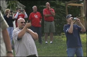 Spectators gather to watch and record the implosion of a portion of the last smokestack at the Acme power plant along the Maumee River in East Toledo.