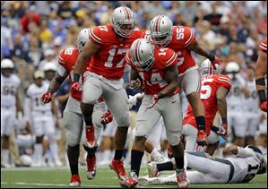 Ohio State linebacker Curtis Grant (14) celebrates with teammates after tackling Navy quarterback Keenan Reynolds, bottom right, and forcing Navy to punt.