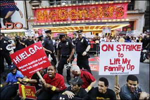 Protesters sit in front of a McDonald's restaurant on 42nd Street in New York's Times Square as police officers move in to begin making arrests.