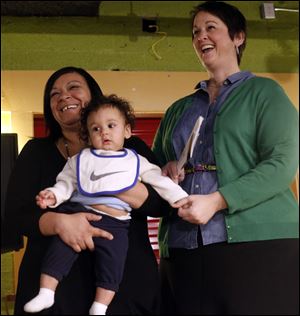 Mom's House Executive Director Christina Rodriguez, left who is holding Carson Wachowiak, 8 months, and who benefits from the program, and Gretchen DeBacker, right, present Sisters-in-Law during a Toledo SOUP event.