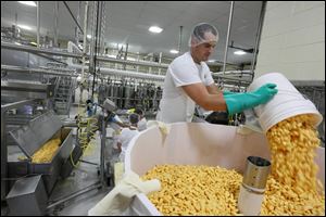 Josh Henning pours cheddar cheese curds into a mold that will become The Andersons’ 4,600-pound Holiday Cheddar at the Henning's Wisconsin Cheese factory in Kiel, Wis.