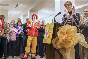 Vicky Brymer, chairman of the Toledo Ronald McDonald House, right, leads a crowd of more than 150 people in cheering during the VIP/donor celebration Wednesday.