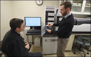 Ryan Carlson, left, and Derek Averill, technical support specialists, explain the operation of the mass spectrometer in the Shimadzu Laboratory for Pharmaceutical Research Excellence at the University of Toledo’s Health Science Campus. The lab, opened in 2015, was dedicated Thursday.