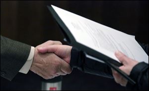 FILE - In this April 22, 2015, file photo, Ralph Logan, general manager of Microtrain, left, shakes hands with a job seeker during a National Career Fairs job fair in Chicago. On Thursday, Nov. 10, 2016, the U.S. Labor Department said that fewer Americans sought unemployment aid during the previous week, the latest sign that companies are holding onto their workers. (AP Photo/M. Spencer Green, File)