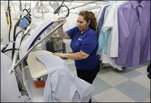 Imelda Abeja uses a hot press on a shirt at the CD One Price Cleaners in Countryside, Ill. As workplaces become more casual and fabrics change to material that can withstand regular washing, the dry cleaning industry is adding services and marketing ploys to stay relevant.