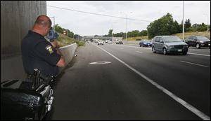 Toledo police officer Tyson Phelan checks the speed of vehicles with a handheld speed detector on I-75 south of the Collingwood Boulevard exit in the central city.