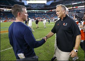 Miami head coach Mark Richt, right, and Toledo head coach Jason Candle shake hands after the Hurricanes beat the Rockets  52-30 last year. This year, the teams meet Saturday at the Glass Bowl.